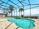 Inviting screened-in pool area with a jacuzzi and palm trees, perfect for relaxation and outdoor living at 5200 Pebble Beach Blvd, Winter Haven, FL 33884