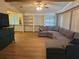 Spacious living room featuring beautiful wood floors, built-in shelving, and a large sectional couch at 6685 Briarhill Dr Ne, Winter Haven, FL 33881