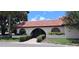 Charming villa exterior featuring a red tile roof and arched entryway surrounded by lush landscaping at 7201 Country Club Dr # G21, Lake Wales, FL 33898