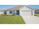 Charming single-story home featuring a two-car garage, blue front door, and neatly manicured lawn at 2173 Emma Ln, Lake Wales, FL 33859