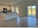 Open-concept kitchen with white cabinets, a center island, stainless steel appliances, and a sliding glass door at 221 Harper Estates Cir, Lake Wales, FL 33859