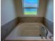 Bright bathroom featuring a large soaking tub with tile surround and a window at 2181 Emma Ln, Lake Wales, FL 33859