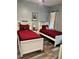 Bright bedroom featuring two twin beds with red bedding, built-in shelving, and wood-look flooring at 837 Oaks Shores Rd, Leesburg, FL 34748