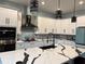 Well lit kitchen with white cabinets, black hardware, modern fixtures, stainless steel appliances, and a beautiful center island at 837 Oaks Shores Rd, Leesburg, FL 34748