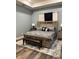 Bright main bedroom with modern decor, including wood-look flooring, a bench at the foot of the bed, and dark accents at 837 Oaks Shores Rd, Leesburg, FL 34748