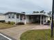 Single-wide manufactured home with covered carport and small front yard at 110 Dogwood Trl, Leesburg, FL 34748