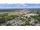 Extensive aerial view of a neighborhood with dense tree coverage and a distant view of a lake, showcasing a desirable location at 1411 Juarez Pl, The Villages, FL 32159