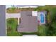 An aerial view highlights a home's backyard with a screened pool, alongside the brick driveway and manicured front yard at 1411 Juarez Pl, The Villages, FL 32159
