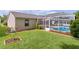 A spacious backyard featuring a screen enclosed in-ground pool and lush green lawn at 1411 Juarez Pl, The Villages, FL 32159