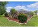 Beautiful landscaping with tropical plants and red mulch surrounds the screened-in pool area at 1411 Juarez Pl, The Villages, FL 32159