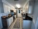 Modern galley kitchen with stainless steel appliances, black countertops, and ample cabinet space at 1618 Juno Trail, Astor, FL 32102
