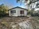 Exterior view of a weathered home with broken windows in an overgrown backyard at 2217 Azalea Ct, Lakeland, FL 33815