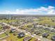Expansive aerial shot showcasing a residential neighborhood with blue skies, green lawns, and a community water tower at 2369 Crossandra St, Mascotte, FL 34753