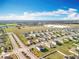 Sprawling aerial view showcases a residential neighborhood bordering green fields and distant industrial buildings under a bright sky at 2369 Crossandra St, Mascotte, FL 34753