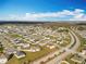 Extensive aerial view displaying a residential neighborhood set against a backdrop of open fields and clear skies at 2369 Crossandra St, Mascotte, FL 34753