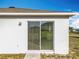 Back patio sliding glass door with vertical blinds, leading to a grassy yard at 2369 Crossandra St, Mascotte, FL 34753