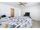 Well-lit bedroom featuring a colorful bedspread, ceiling fan, and view into the en-suite bath, creating a comfortable space at 2369 Crossandra St, Mascotte, FL 34753