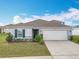 Charming single-story home with a two car garage, landscaped front yard, and a well-maintained lawn at 2369 Crossandra St, Mascotte, FL 34753
