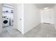 Hallway with tile floors leading past the laundry area with modern appliances at 2369 Crossandra St, Mascotte, FL 34753