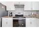 Close-up of modern kitchen appliances, mosaic backsplash, granite counters, and sleek white cabinetry at 2369 Crossandra St, Mascotte, FL 34753