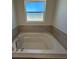 A relaxing, tiled bathtub with chrome hardware is placed under a frosted window at 277 Harper Estates Cir, Lake Wales, FL 33859