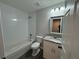 Bright bathroom featuring a tub, toilet, and vanity with a granite countertop and decorative mirror at 412 Avenue M Ne, Winter Haven, FL 33881