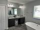 Bright bathroom featuring double vanity, granite counters, soaking tub, and gray tile flooring at 414 Taft Dr, Davenport, FL 33837