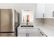 Close-up of modern kitchen featuring stainless steel fridge, quartz countertops, and white cabinets at 708 Wynn Dr, Sanford, FL 32773