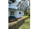Exterior view of home with sliding door leading to a lushly landscaped yard at 103 Bougainvillea Dr, Leesburg, FL 34748
