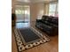 Living room features wood-look flooring, area rug, furniture, sliding door to sun room at 103 Bougainvillea Dr, Leesburg, FL 34748