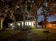Charming home with a well-lit driveway, lush greenery and mature trees at 106 Royal Palm Dr, Leesburg, FL 34748