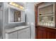 Bright bathroom with a wood door leading to outside, features a modern vanity and a well-lit mirror at 1107 Linmar Ave, Fruitland Park, FL 34731