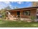 Single-story home boasting a welcoming front porch and natural wood siding, blending seamlessly with the outdoor surroundings at 1107 Linmar Ave, Fruitland Park, FL 34731