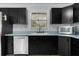 Kitchen featuring black cabinets, white appliances, and a window over the sink at 1107 Linmar Ave, Fruitland Park, FL 34731