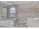 Bathroom with tiled shower and walls, as well as a bathtub beneath a window at 1134 Norwood Dr, Deltona, FL 32725