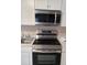 Close-up of stainless steel oven, cooktop, microwave, and sink with white cabinets and countertops in a modern kitchen at 134 Daytona Ave, Daytona Beach, FL 32117