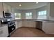 Well-lit kitchen featuring stainless steel appliances, granite countertops, white cabinets, and wood-look tile at 141 W 6Th St, Frostproof, FL 33843