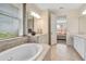 Bathroom featuring a soaking tub, large window, and vanity with stone countertop at 1447 Myrtle Oaks Trl, Oviedo, FL 32765