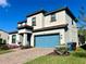 View of the side of the two-story home with a blue garage door and manicured lawn at 207 Aidans Lndg, Haines City, FL 33844