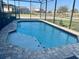 Sparkling blue pool in screened-in enclosure, surrounded by a brick patio at 207 Aidans Lndg, Haines City, FL 33844