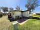Exterior view of home featuring a well-maintained backyard with a small patio area, a golf cart and mature trees at 207 Jacaranda Dr, Leesburg, FL 34748
