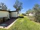 Exterior view of the backyard featuring green grass, a patio area, trash cans and a view of surrounding houses at 207 Jacaranda Dr, Leesburg, FL 34748