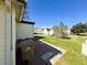 Exterior view of the backyard featuring green grass, a patio area, trash cans and view of surrounding houses at 207 Jacaranda Dr, Leesburg, FL 34748