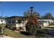 Well-kept front yard featuring a mature palm tree, colorful flowering bushes, and neatly trimmed landscaping at 207 Jacaranda Dr, Leesburg, FL 34748