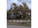 Picturesque backyard featuring a mature tree, complemented by a white picket fence, creating a serene outdoor space at 225 E Cummings St, Lake Alfred, FL 33850