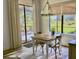 Bright dining area with chandelier, wooden table, neutral curtains, and sliding glass doors to patio at 25879 Crossings Bluff Ln, Sorrento, FL 32776