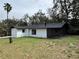 View of the rear of the white home with a screened porch, black trim, and a well-maintained yard at 303 E Fountain St, Fruitland Park, FL 34731