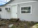 The home's exterior features a window, air conditioner, and a white front door with steps at 309 Old Mission Rd, New Smyrna Beach, FL 32168