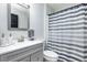 Bathroom with a gray vanity, white sink and toilet, and gray and white striped shower curtain at 402 Bramble Way, Minneola, FL 34715
