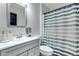 Bathroom with a gray vanity, white sink and toilet, and gray and white striped shower curtain at 402 Bramble Way, Minneola, FL 34715